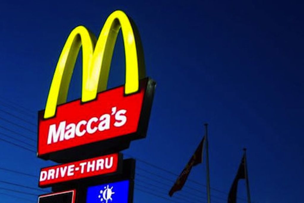A typical red McDonalds sign with yellow arches that reads "Macca's" instead.