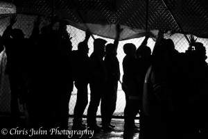 B&W picture of people holding a tarp up to a fence