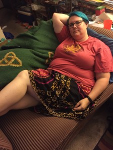 A fat woman in teeshirt and skirt lounging on a couch